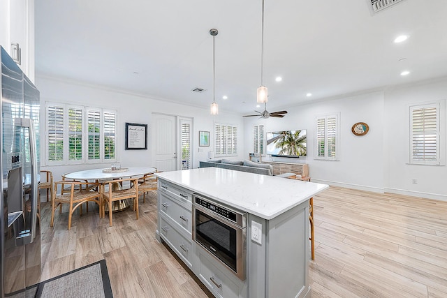 kitchen with ceiling fan, a center island, light hardwood / wood-style floors, and decorative light fixtures