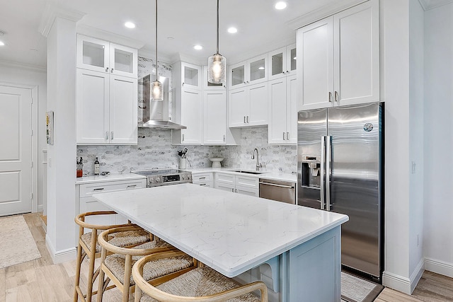 kitchen featuring a center island, a kitchen breakfast bar, wall chimney range hood, decorative backsplash, and stainless steel appliances