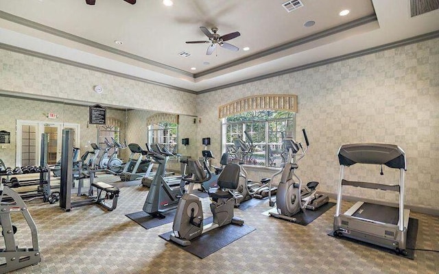 gym with ceiling fan, ornamental molding, a raised ceiling, and carpet flooring