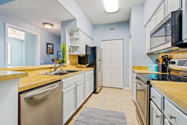 kitchen featuring sink, white cabinets, light tile patterned floors, and appliances with stainless steel finishes