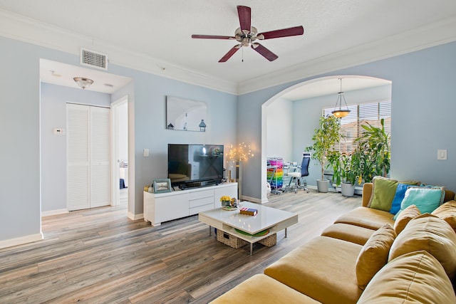 living room featuring ceiling fan, hardwood / wood-style floors, ornamental molding, and a textured ceiling