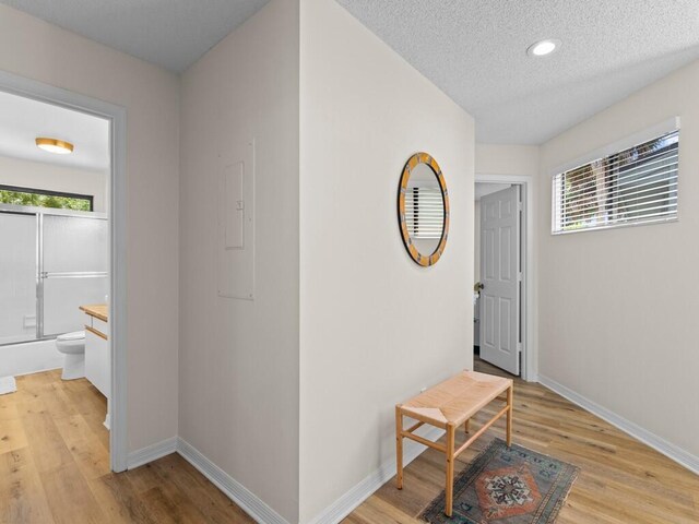 corridor with a textured ceiling and light hardwood / wood-style floors