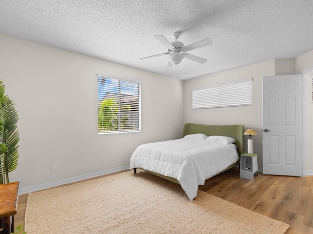 bedroom with ceiling fan, a textured ceiling, and hardwood / wood-style floors