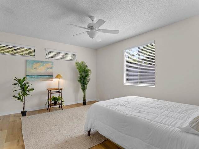 bedroom featuring light hardwood / wood-style floors, a textured ceiling, and ceiling fan