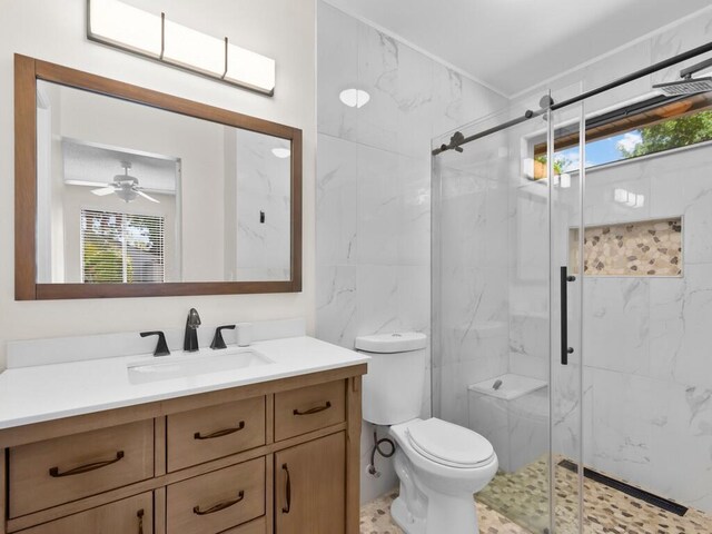 bathroom with vanity, toilet, an enclosed shower, and ceiling fan