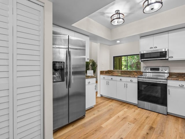 kitchen with appliances with stainless steel finishes, white cabinetry, and light wood-type flooring