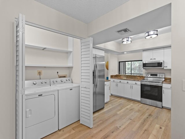 kitchen with washer and clothes dryer, white cabinetry, appliances with stainless steel finishes, a textured ceiling, and light hardwood / wood-style floors