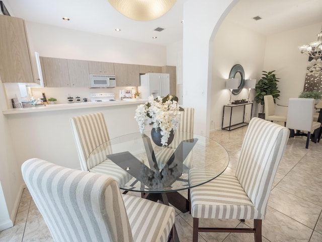 dining area with a chandelier, arched walkways, and visible vents