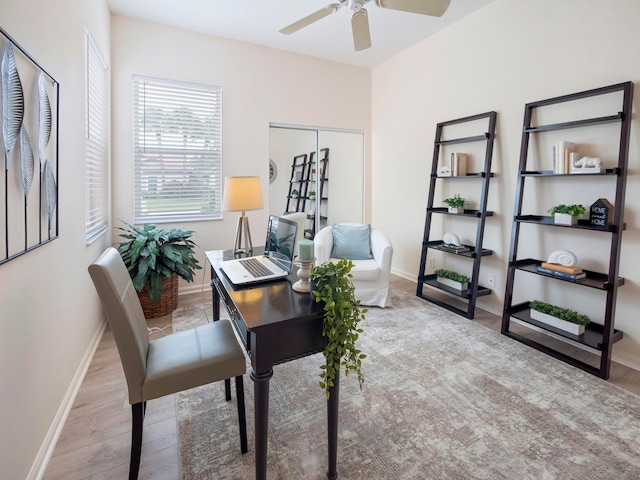 office with light wood-type flooring and ceiling fan