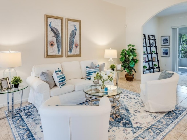 tiled living room featuring baseboards and arched walkways