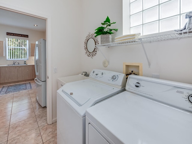 clothes washing area with separate washer and dryer, sink, and light tile patterned floors