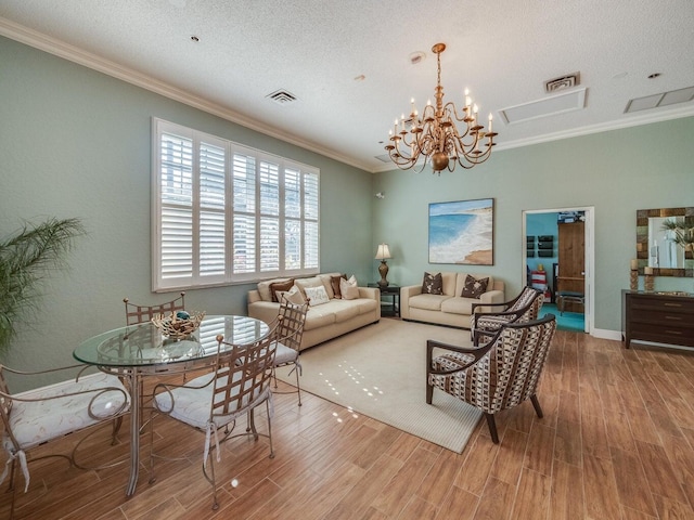 living room featuring hardwood / wood-style flooring, ornamental molding, a textured ceiling, and an inviting chandelier