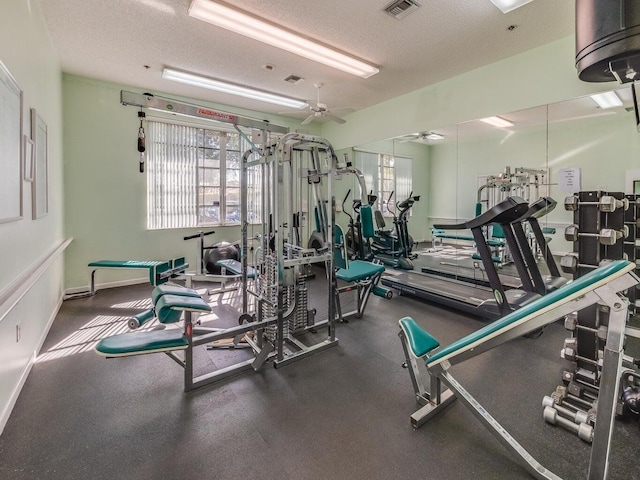 exercise room with a textured ceiling, ceiling fan, visible vents, and baseboards