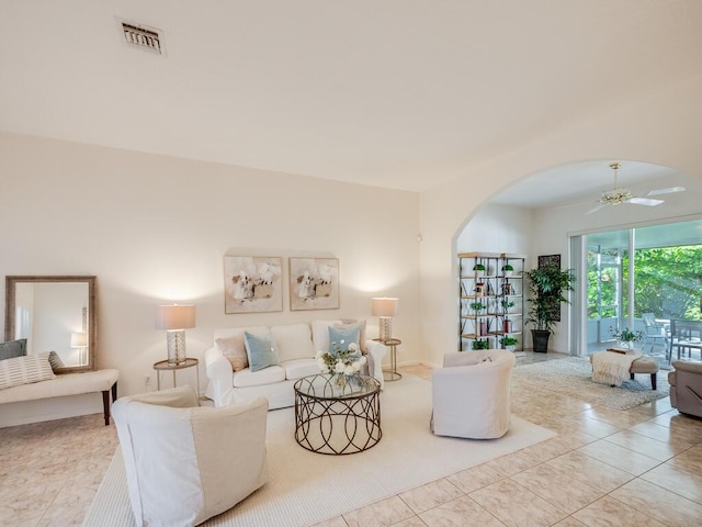 living room with arched walkways, visible vents, and ceiling fan