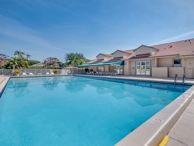 community pool featuring french doors, fence, and a patio