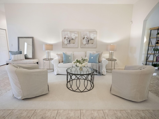 living room with arched walkways and marble finish floor