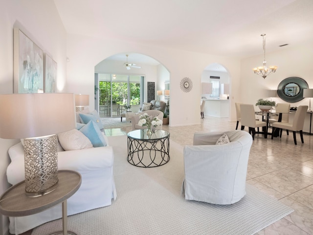 tiled living room with ceiling fan with notable chandelier