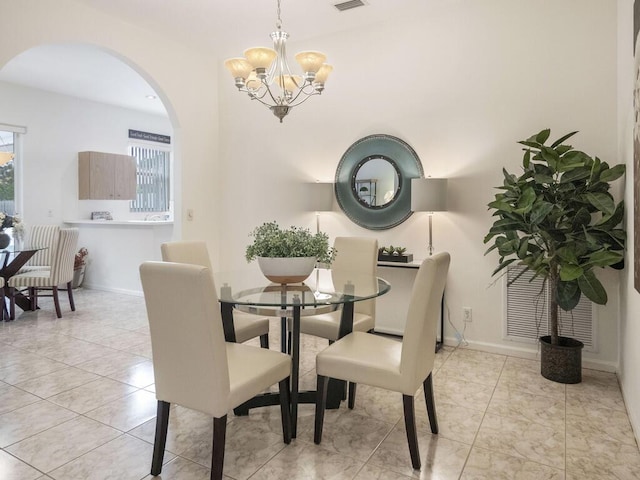 dining space with arched walkways, a notable chandelier, visible vents, tile patterned flooring, and baseboards