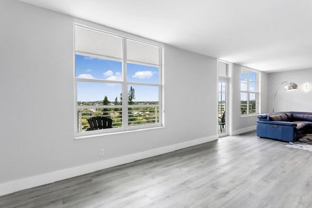 unfurnished living room featuring a healthy amount of sunlight, baseboards, and wood finished floors