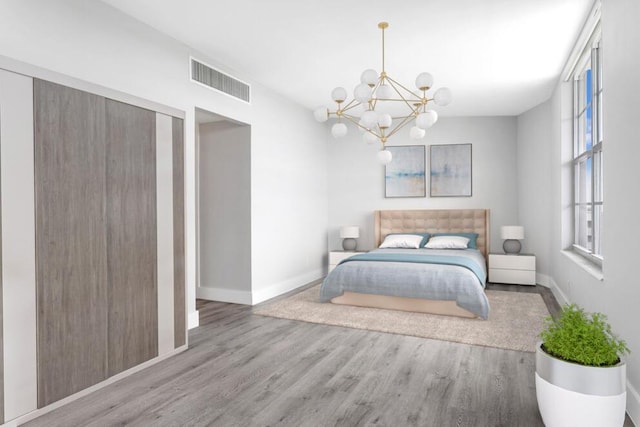 bedroom featuring a notable chandelier, wood finished floors, visible vents, and baseboards