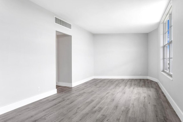 unfurnished room featuring baseboards, visible vents, and wood finished floors