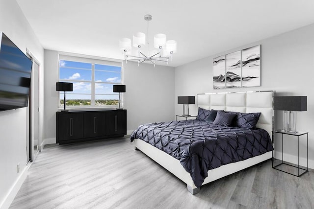 bedroom featuring an inviting chandelier, baseboards, and wood finished floors