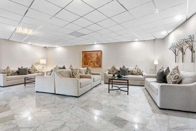 living area featuring a paneled ceiling and marble finish floor