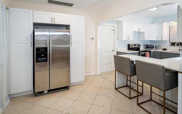 kitchen with white cabinetry, appliances with stainless steel finishes, sink, and light tile patterned floors