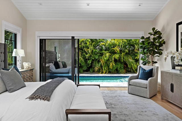 bedroom with access to outside, vaulted ceiling, multiple windows, and light wood-type flooring