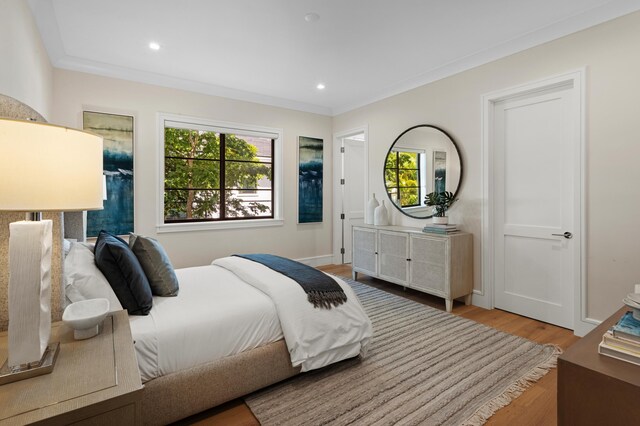 bedroom with multiple windows, light wood-type flooring, and ornamental molding