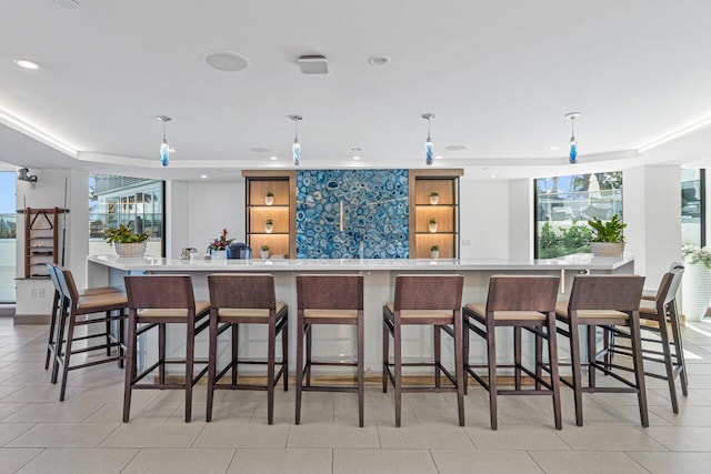 kitchen featuring a wealth of natural light, decorative light fixtures, and a breakfast bar