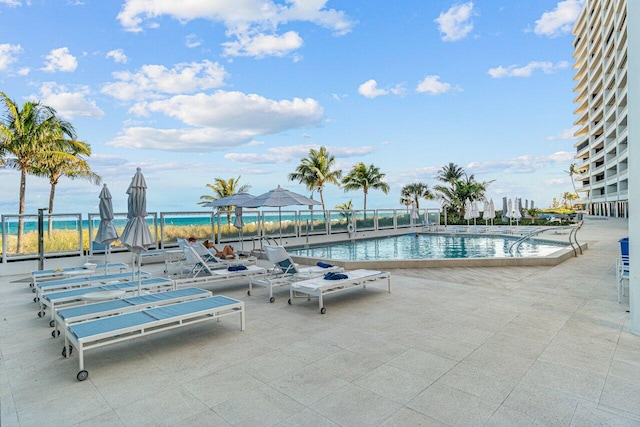 view of swimming pool with a water view and a patio