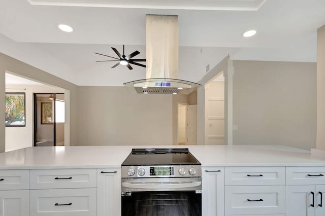 kitchen with stainless steel range with electric stovetop, island range hood, light countertops, white cabinets, and recessed lighting