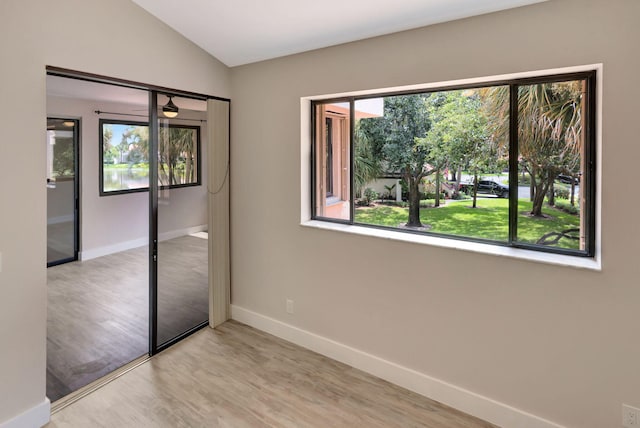 unfurnished bedroom featuring light hardwood / wood-style floors, lofted ceiling, and a closet