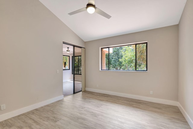 spare room featuring light wood-type flooring, vaulted ceiling, a ceiling fan, and baseboards