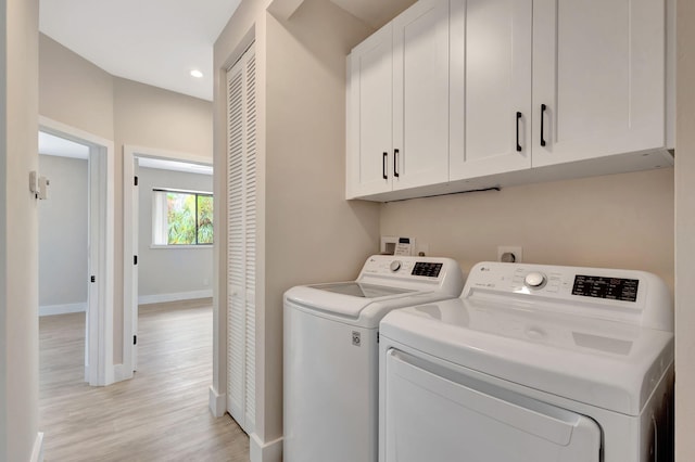 clothes washing area featuring cabinets, washer and dryer, and light hardwood / wood-style flooring