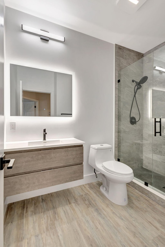 bathroom featuring a shower with door, wood-type flooring, toilet, and vanity