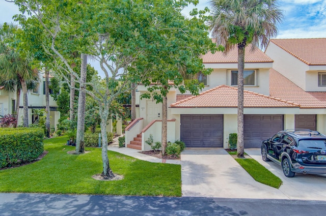 view of front of home with stucco siding, a tiled roof, concrete driveway, a front lawn, and an attached garage