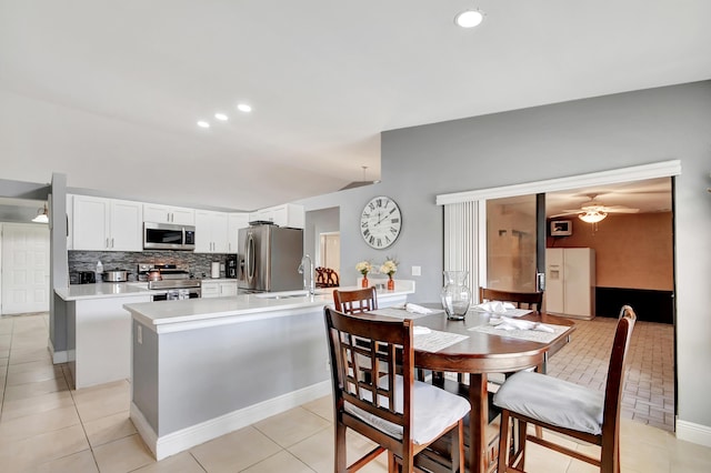 kitchen with light tile patterned floors, white cabinetry, stainless steel appliances, and a kitchen island with sink