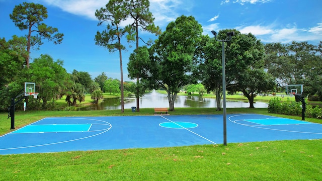 view of basketball court featuring a lawn and a water view