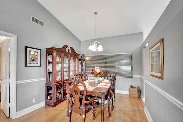 dining space featuring a chandelier, lofted ceiling, and light wood-type flooring