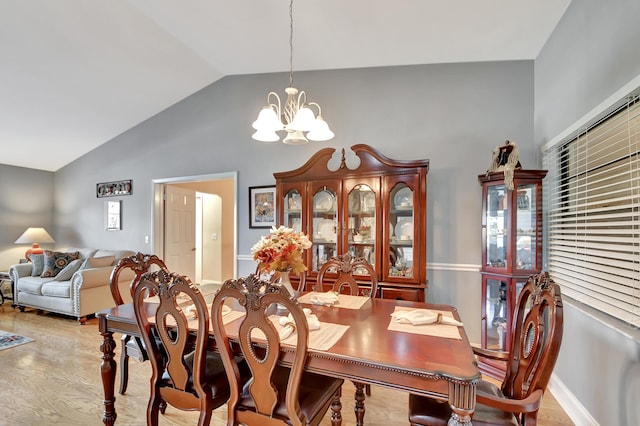 dining area featuring a chandelier, lofted ceiling, and light hardwood / wood-style floors