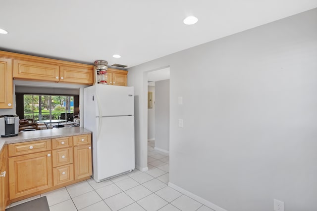 kitchen with white refrigerator, light tile patterned flooring, and light brown cabinets