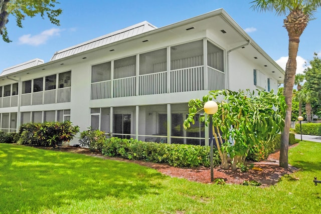1854 SW Palm City Rd Unit 101, Stuart, FL 34994 - back of house featuring a yard, a sunroom, stucco siding, a standing seam roof, and metal roof