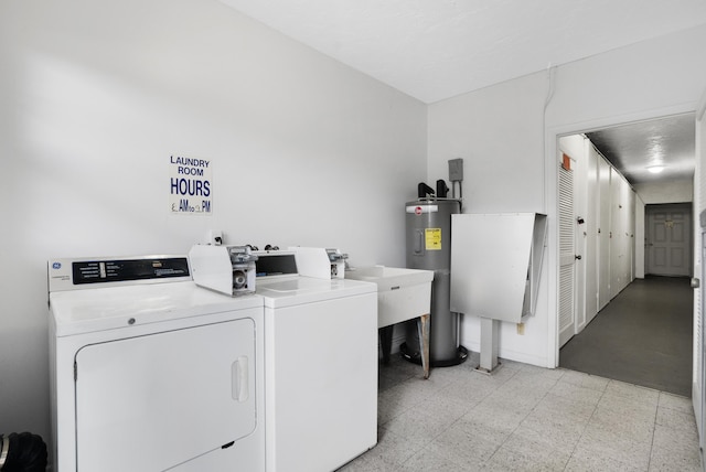 clothes washing area featuring separate washer and dryer, electric water heater, and sink