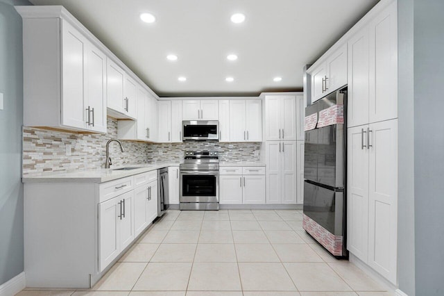 kitchen with sink, white cabinets, light tile patterned floors, appliances with stainless steel finishes, and tasteful backsplash