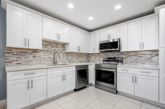 kitchen with stainless steel appliances, light tile patterned flooring, sink, and white cabinets