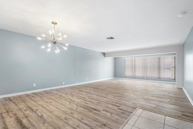 empty room with a chandelier and light hardwood / wood-style floors