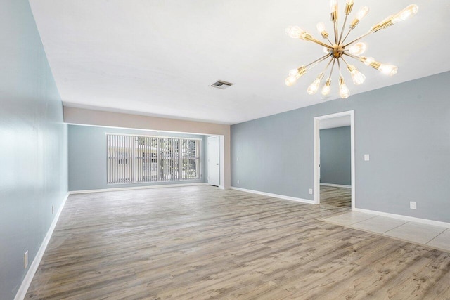 spare room featuring a chandelier and light hardwood / wood-style flooring