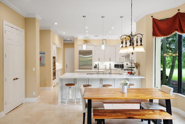 kitchen with appliances with stainless steel finishes, decorative light fixtures, white cabinets, a kitchen breakfast bar, and ornamental molding